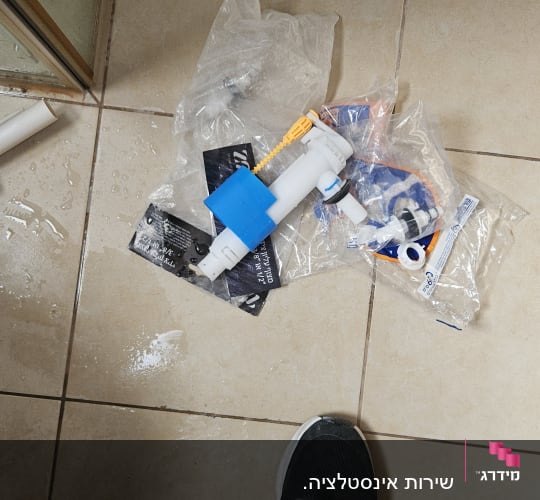 חלקי אינסטלציה על רצפת אריחים רטובה